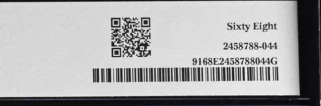 Back label of the same PMG holder, with a QR code, the grade written out as Sixty Eight and certification number 2458788-044 above a barcode